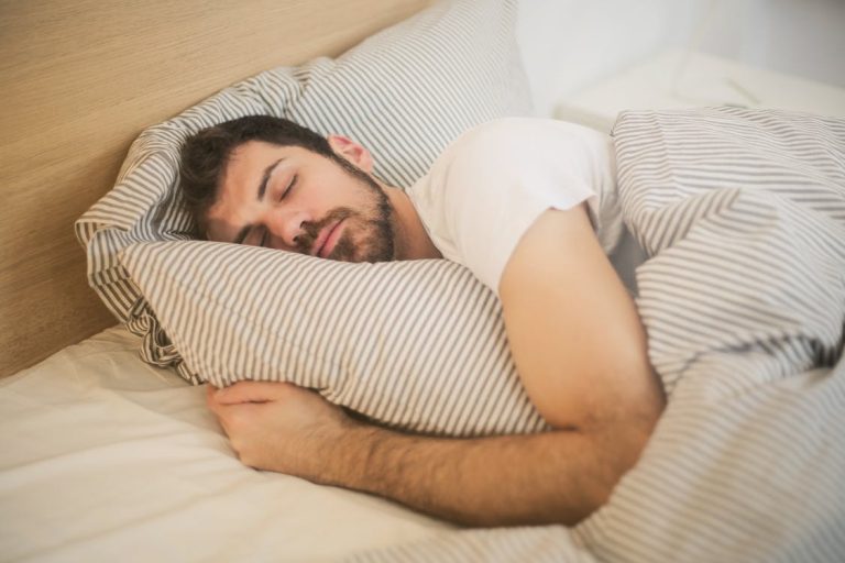 Higiene del sueño: guía práctica para dormir mejor cada noche Persona durmiendo plácidamente en una cama cómoda con luz tenue